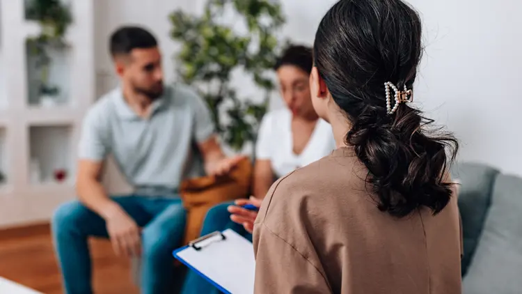 A young couple actively participates in a pre-conception counselling for couples with their gynaecologist at a women's health clinic.